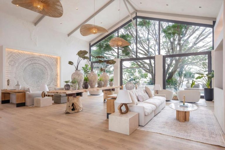 Elegante lobby del The Retreat Costa Rica Wellness Resort con decoración natural, sofás blancos y grandes ventanales con vistas al bosque