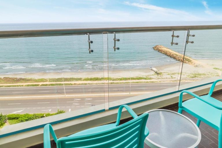 Balcón con sillas turquesa y vista panorámica al mar y playa en Hotel GHL Corales de Indias