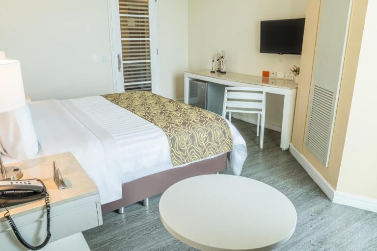 Habitación doble moderna con cama king, escritorio blanco y TV en Hotel GHL Corales de Indias
