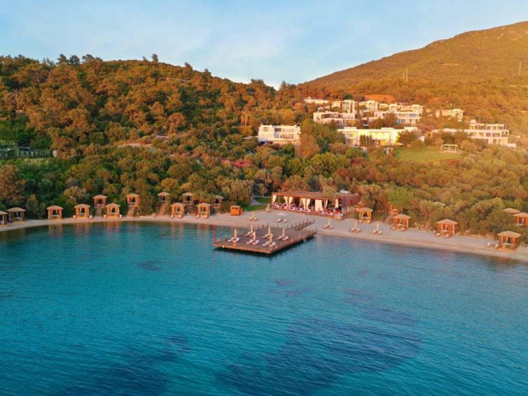 Vista aérea de la playa privada con embarcadero y cabañas del Rixos Premium Bodrum en Turquía