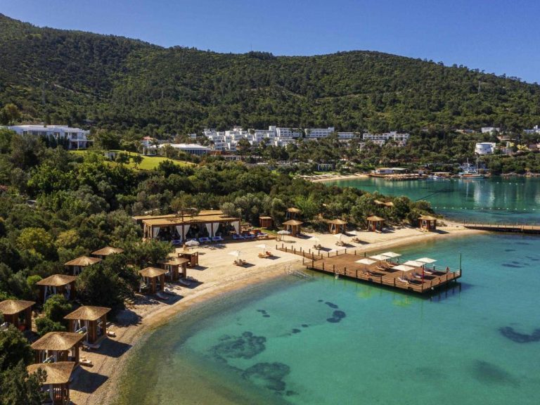 Vista aérea de la playa privada y embarcadero del Rixos Premium Bodrum con aguas turquesas
