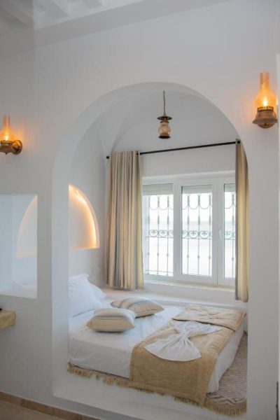 Habitación con arco blanco y cama doble de estilo mediterráneo en el Hôtel Al Jazira Mahdia