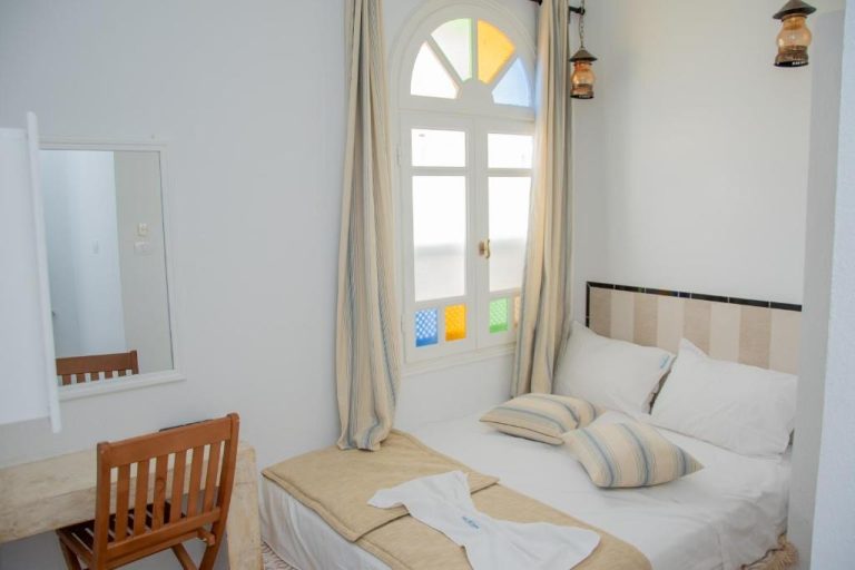 Habitación doble con ventana de colores y cama en blanco del Hôtel Al Jazira Mahdia