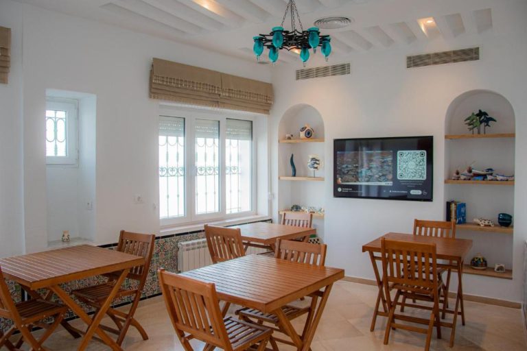 Salón comedor con mesas de madera y televisor del Hôtel Al Jazira Mahdia en Túnez