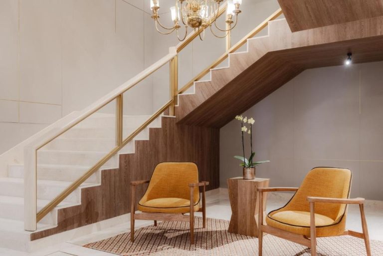 Elegante escalera de madera con barandilla dorada y sillones amarillos en el lobby del Four Points by Sheraton Tequendama Bogotá