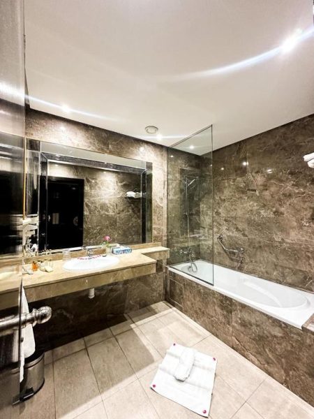 Baño de lujo con bañera y revestimiento de mármol oscuro en el Hotel Royal Mirage Deluxe