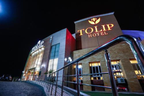 Fachada exterior iluminada del Tolip Hotel New Cairo durante la noche con acceso principal