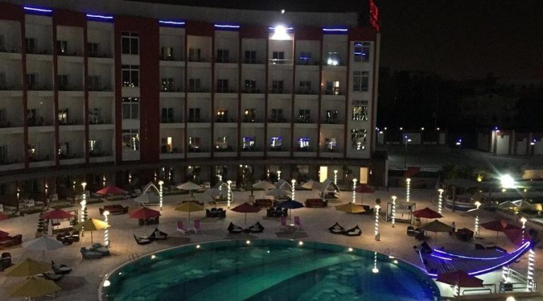 Piscina exterior iluminada de noche con tumbonas y sombrillas en el Hotel Tulip New Cairo