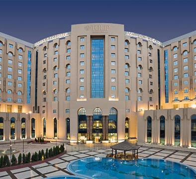 Fachada iluminada del Tulip New Cairo Hotel con piscina exterior y jardines en El Cairo