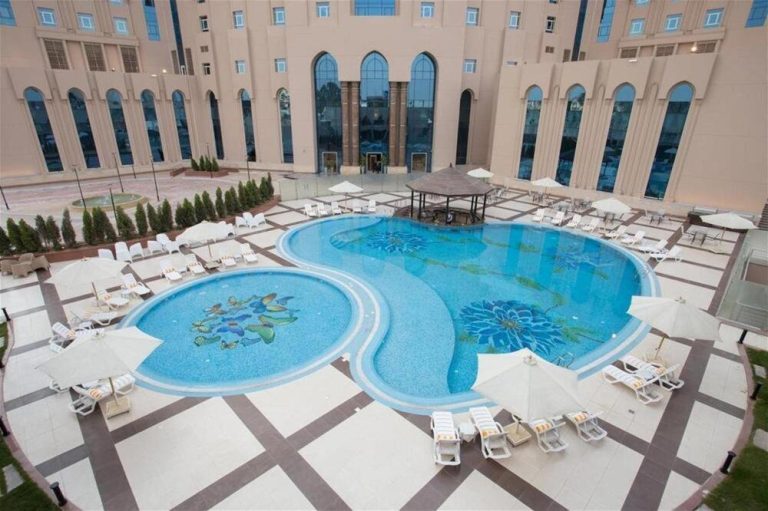 Piscina exterior con diseño yin-yang y mosaicos decorativos del Tulip New Cairo rodeada de tumbonas