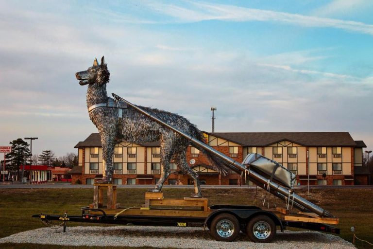 Escultura gigante de lobo metálico frente al Super 8 by Wyndham Cuba sobre remolque