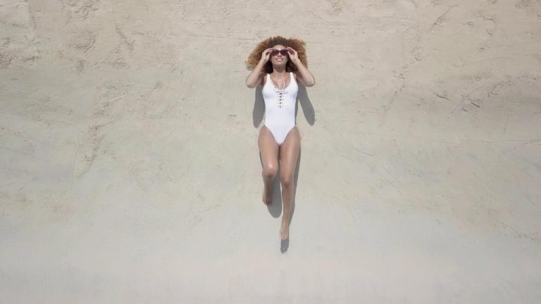 Mujer tomando el sol en la playa de arena blanca del Azul Beach Resort Negril by Karisma