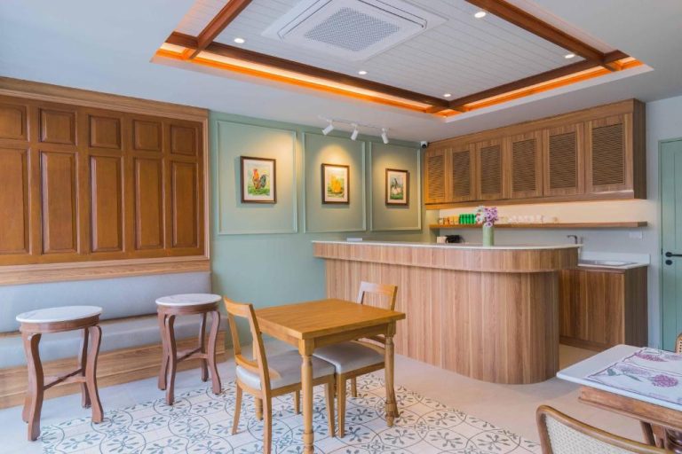 Recepción y zona de desayuno con decoración colonial de madera en TUAN Hotel Bangkok cerca de Wat Arun