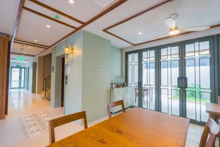 Comedor interior con mesas de madera y puertas acristaladas en TUAN Hotel Bangkok cerca de Wat Arun