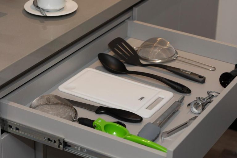 Cajón de cocina con utensilios del Altus Hotel, incluyendo tabla de cortar, espátulas y coladores