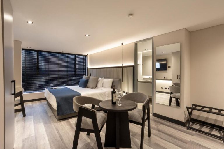 Habitación deluxe con cama doble, mesa y copa de vino en el Altus Hotel con diseño moderno