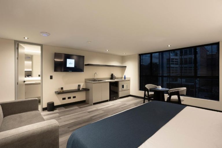 Suite moderna con kitchenette, televisor y zona de trabajo en Altus Hotel