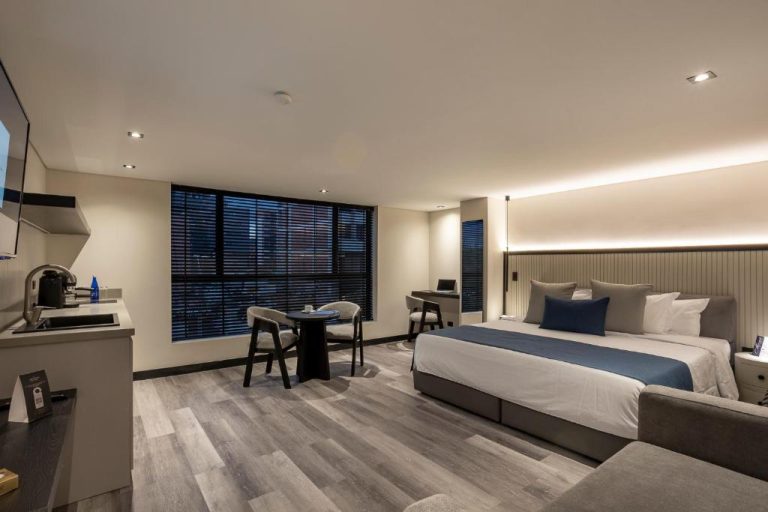 Habitación deluxe con cama king size y sala de estar en Altus Hotel, diseño moderno y elegante