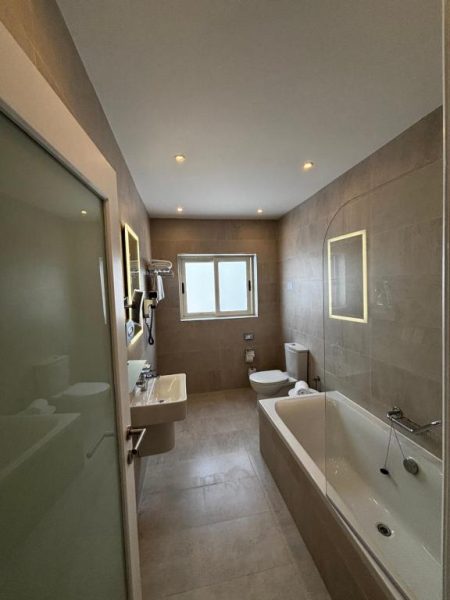 Baño completo con bañera, lavabo y ducha del Osborne Hotel, acabados modernos en tonos beige