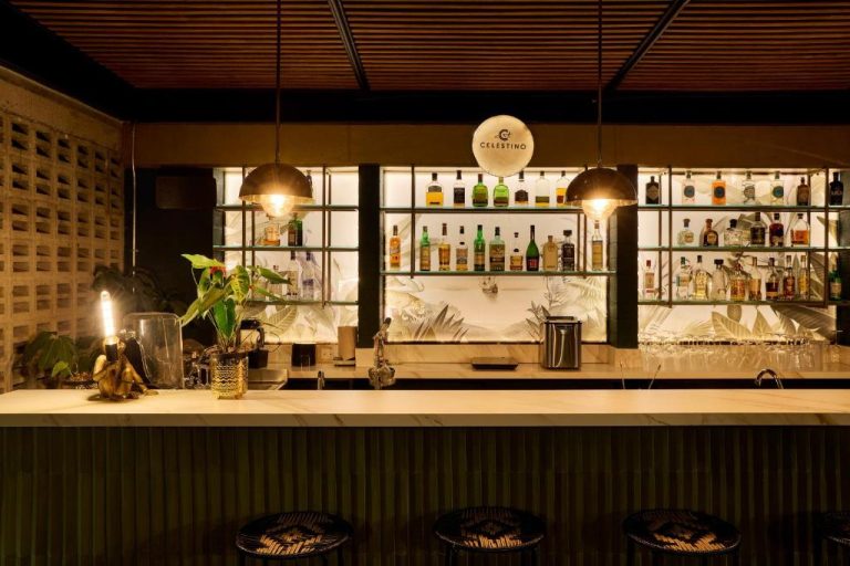 Bar de cócteles con estantería iluminada y amplia selección de licores en Celestino Boutique Hotel & Spa