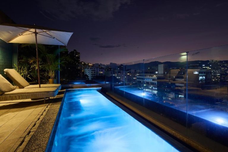 Piscina infinita en la azotea del Celestino Boutique Hotel & Spa iluminada de noche con vistas a la ciudad