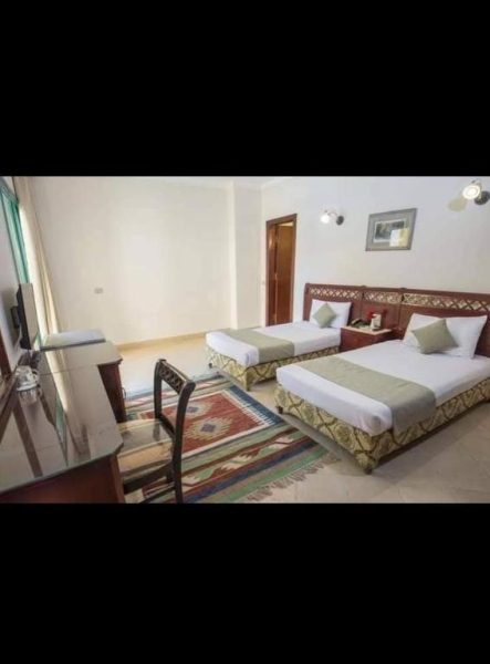 Habitación triple con dos camas y escritorio en la Qaryat Al Dahabia, decoración clásica y alfombra tradicional