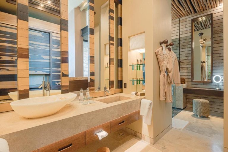 Baño de suite de lujo con lavabos de mármol y batas en La Casa de la Playa by Xcaret