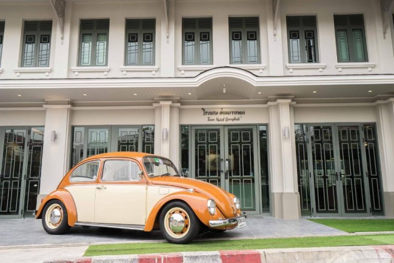 Fachada colonial del Tuan Hotel Bangkok cerca de Wat Arun con Volkswagen Beetle vintage naranja