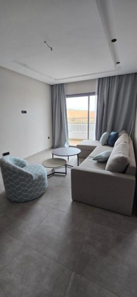 Salón moderno con sofá y sillas en L'Escale Appart-Hôtel by 7AV Hotels con balcón y luz natural