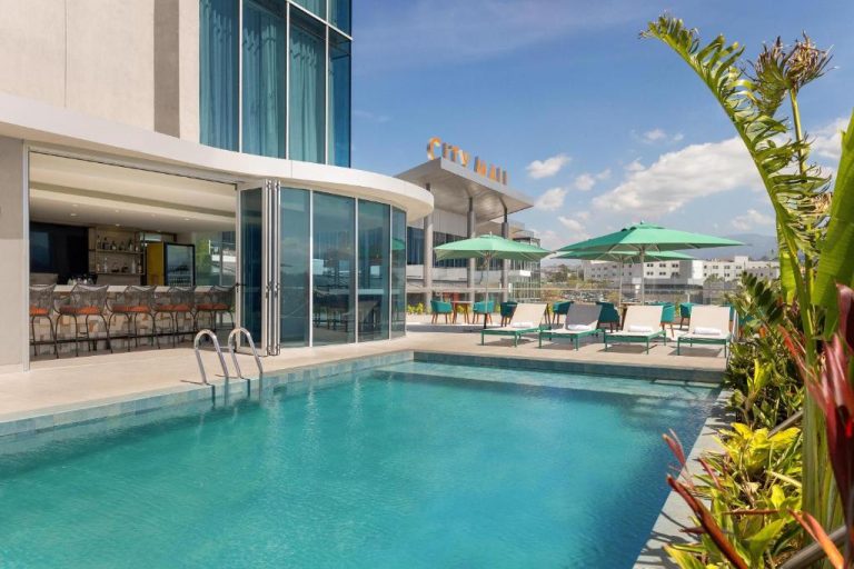 Piscina exterior en terraza con tumbonas y bar del Hilton Garden Inn San José Airport City Mall