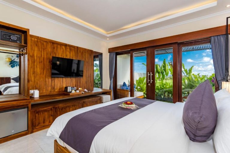 Habitación de lujo con cama doble y vistas al jardín tropical en Svadarma Bali Villa by Dhananjaya