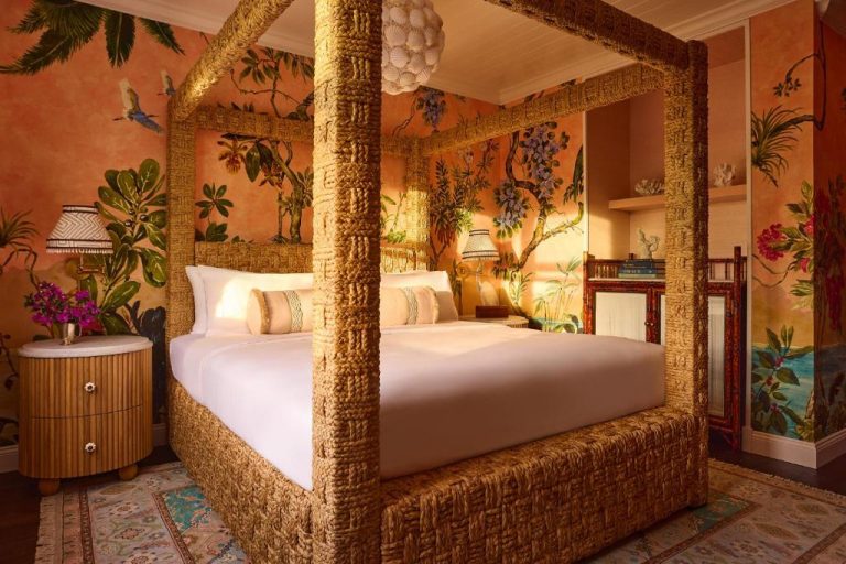 Habitación de lujo con cama de dosel de mimbre y murales tropicales en Coral Sands Inn & Cottages