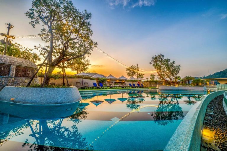 Piscina exterior al atardecer con tumbonas y jardín tropical en HOMA Phuket Town, Tailandia