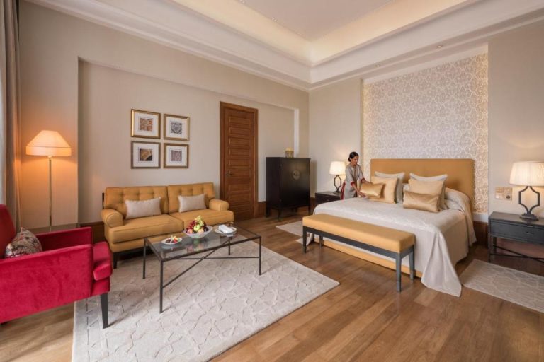 Suite junior de lujo con cama dorada y zona de estar en The Oberoi Marrakech