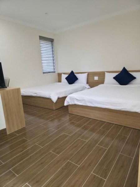 Habitación doble con dos camas y suelo de madera en el Huỳnh Nga Măng Đen Hotel