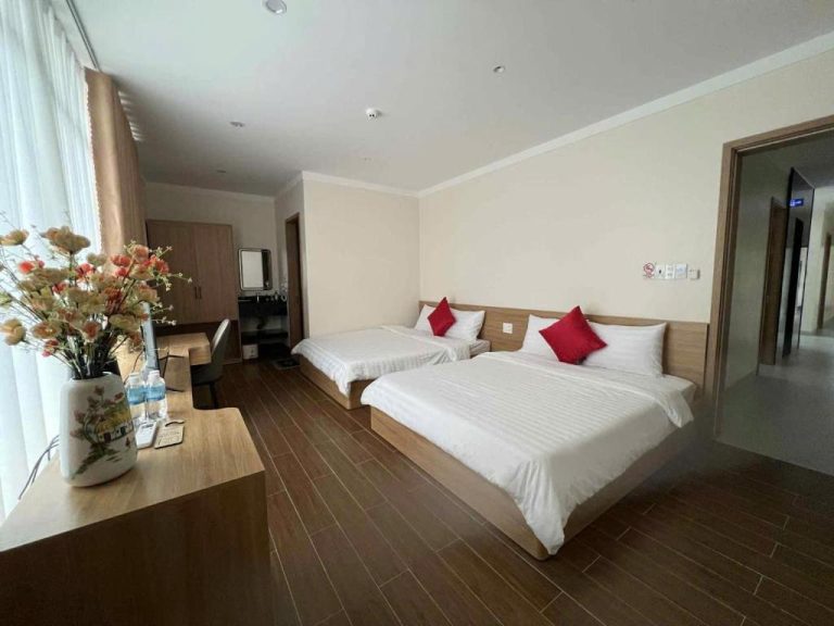 Habitación doble con dos camas y almohadas rojas en el Huỳnh Nga Măng Đen Hotel