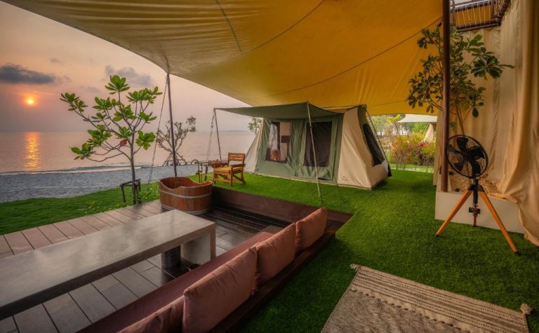 Zona de glamping con tienda de campaña y vistas al mar al atardecer en Camp Cayla COASTA