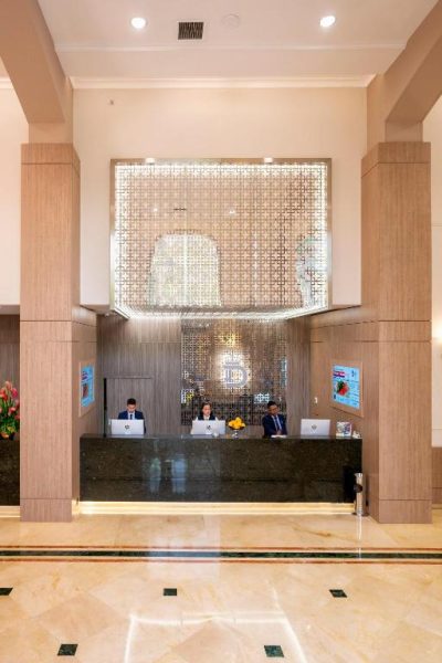 Recepción principal con mostrador de mármol y personal atendiendo en el Hotel Dann Carlton Medellín