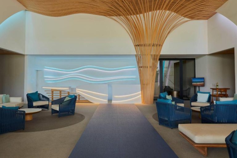 Lobby del Radisson Blu Aruba con sillones azules, columna de madera y decoración de ondas iluminadas