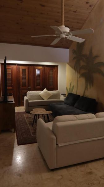 Sala de estar con sofás blancos, ventilador de techo y decoración tropical en Selectum Hacienda Punta Cana
