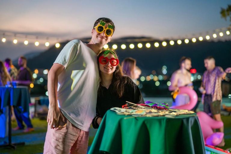 Pareja con gafas de fiesta divirtiéndose en la terraza nocturna del HOMA Phuket Town