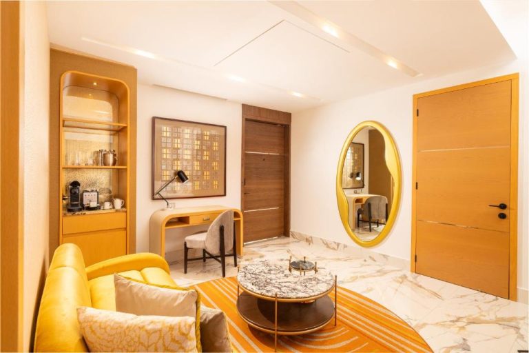 Elegante salón de suite con sofá amarillo y espejo dorado en Garza Blanca Sanctuary Puerto Vallarta