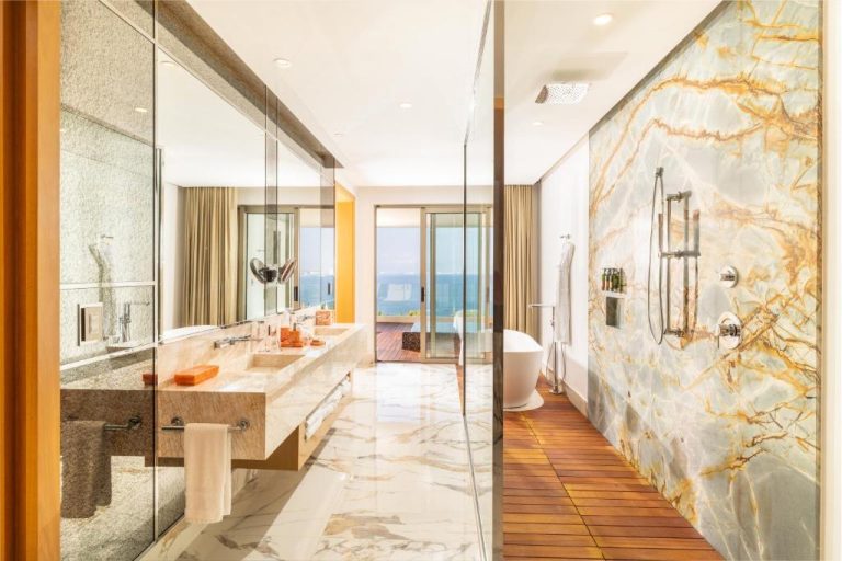 Lujoso baño de mármol con ducha de lluvia y bañera independiente con vista al mar en Garza Blanca Sanctuary Puerto Vallarta