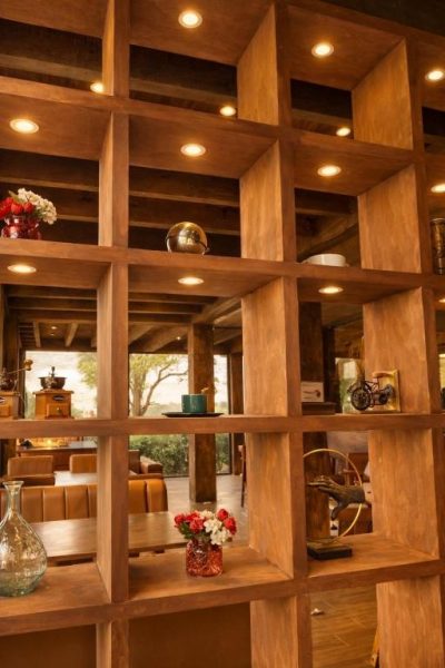Estantería de madera con iluminación empotrada y decoración artesanal en Orgánico Hotel Boutique