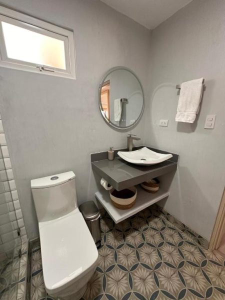 Baño moderno con lavabo de porcelana y suelo de mosaico en La Riviera Hotel