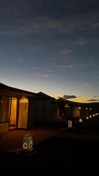 Exterior del Velaria Luxury Camp al atardecer con faroles decorativos iluminando las carpas de lujo en el desierto