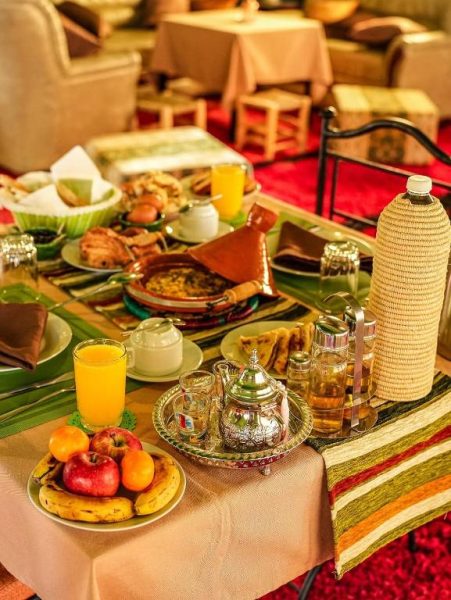 Desayuno tradicional marroquí con té, tajín y frutas frescas en Velaria Luxury Camp