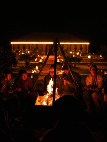 Huéspedes reunidos alrededor de una fogata nocturna en Velaria Luxury Camp con iluminación ambiental
