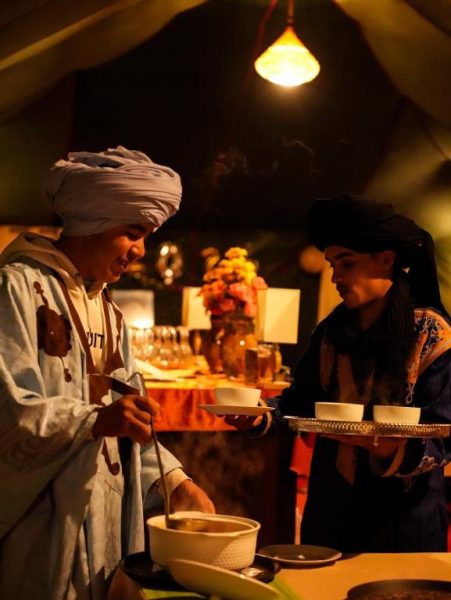 Servicio de té tradicional bereber en la carpa del Velaria Luxury Camp bajo iluminación cálida