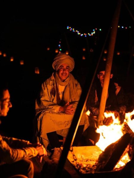 Huéspedes reunidos alrededor de una fogata nocturna en el Velaria Luxury Camp en el desierto